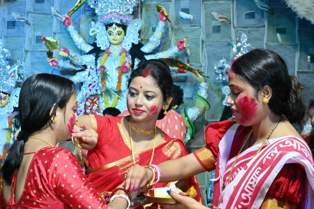 Women joyfully smear each other with Vermillion as part of the exuberant Durga Puja festival celebrations in India.